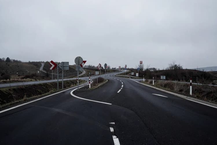 Uma estrada com várias placas de trânsito confusas e caminhos divergentes.